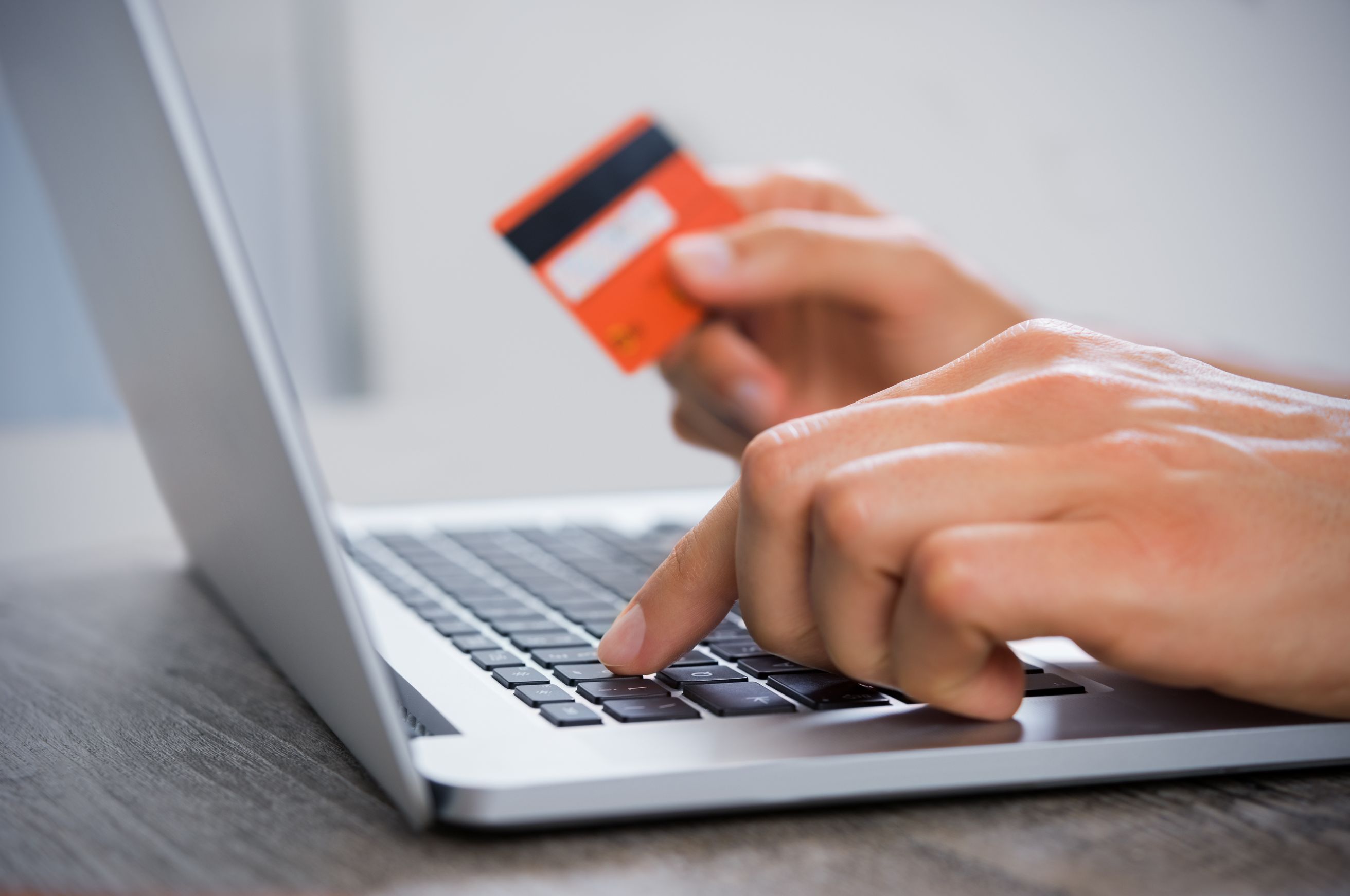 closeup of person holding credit card and pointing to computer key