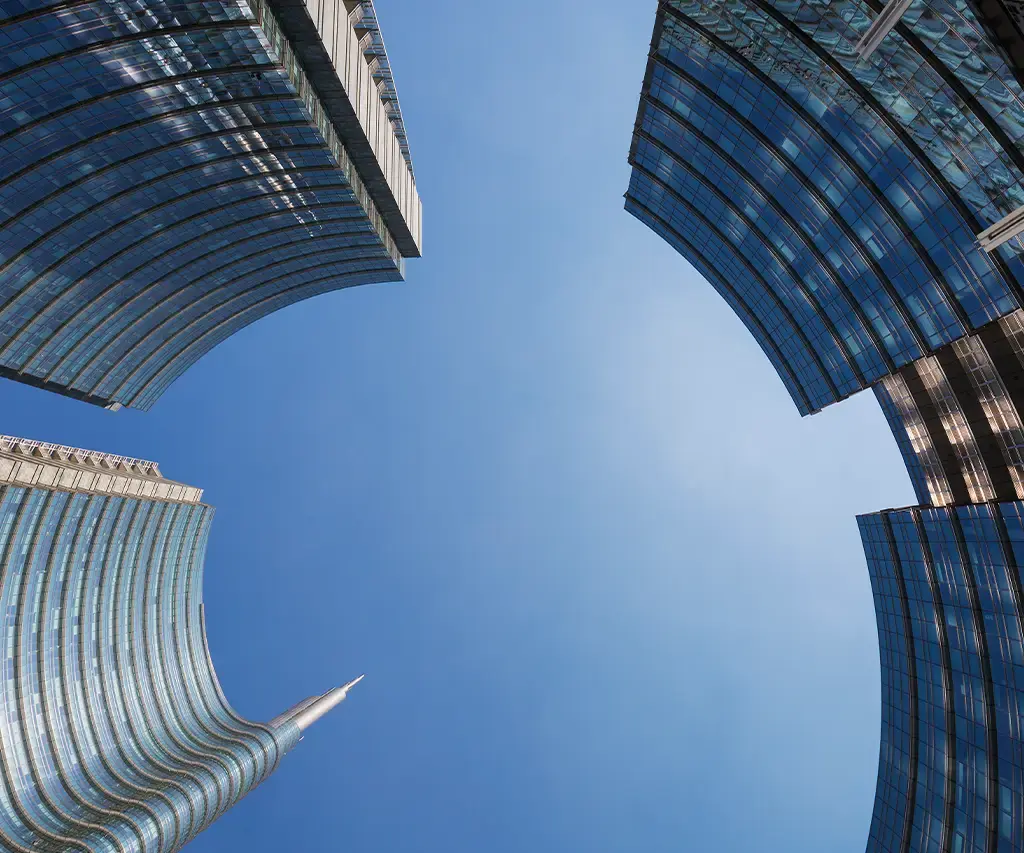 Upward view of modern glass skyscrapers against a clear blue sky in a financial district.