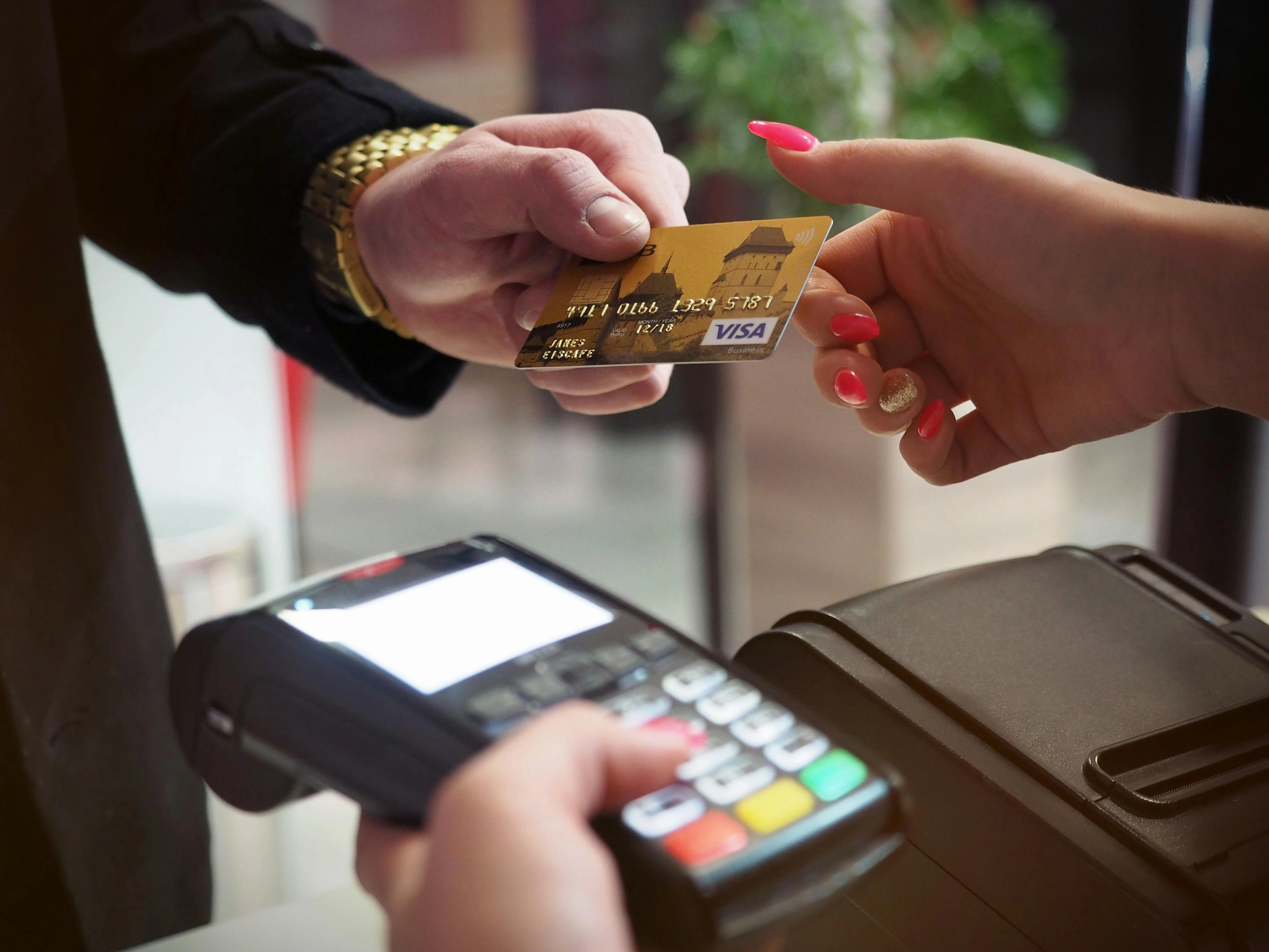A person holding a credit card and paying at a cash register.