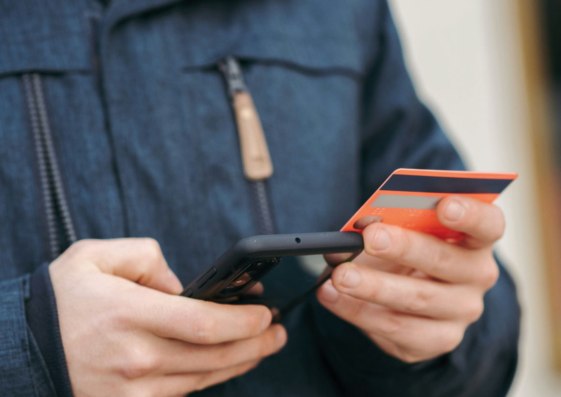 man in jacket holding phone and credit card