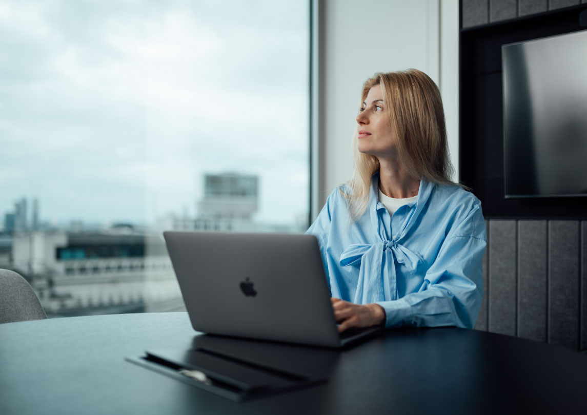 person using laptop next to window