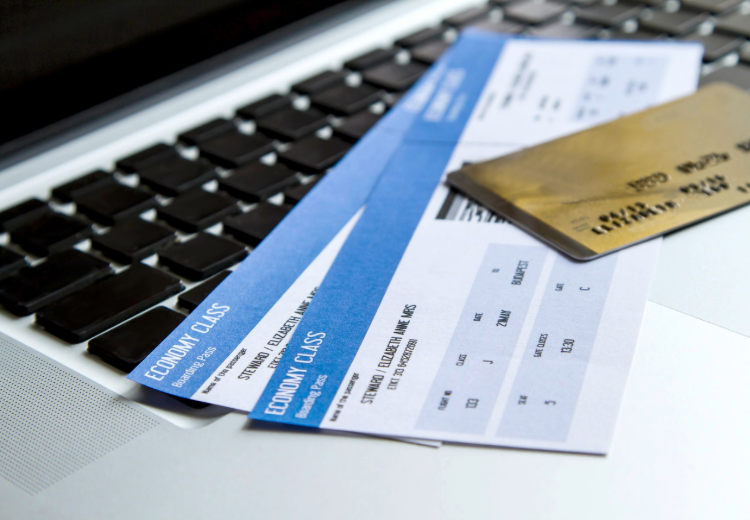 Two airplane tickets and a credit card over a laptop keyboard
