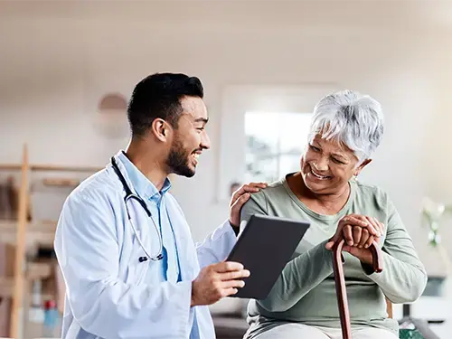 A doctor engages in a conversation with an elderly woman, ensuring seamless connectivity at the Point of Care.