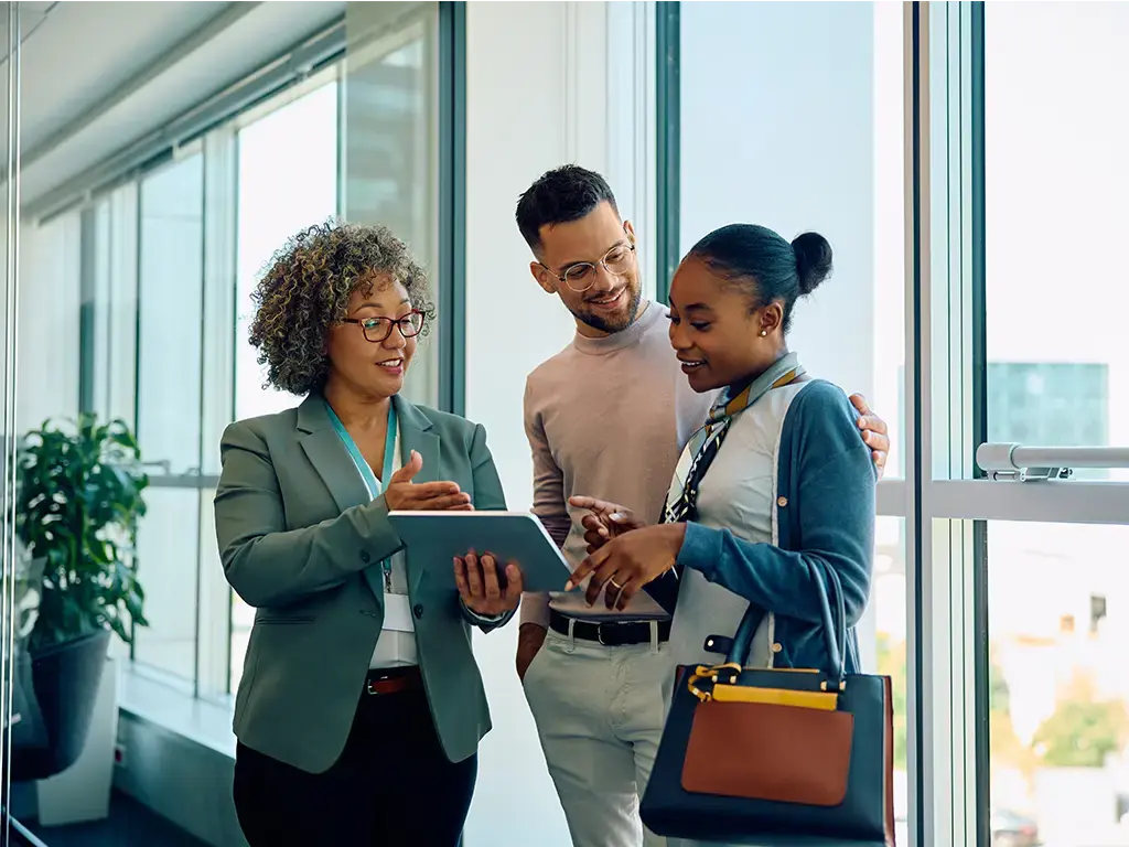 Salesperson showing details on a tablet to a couple in a modern office setting