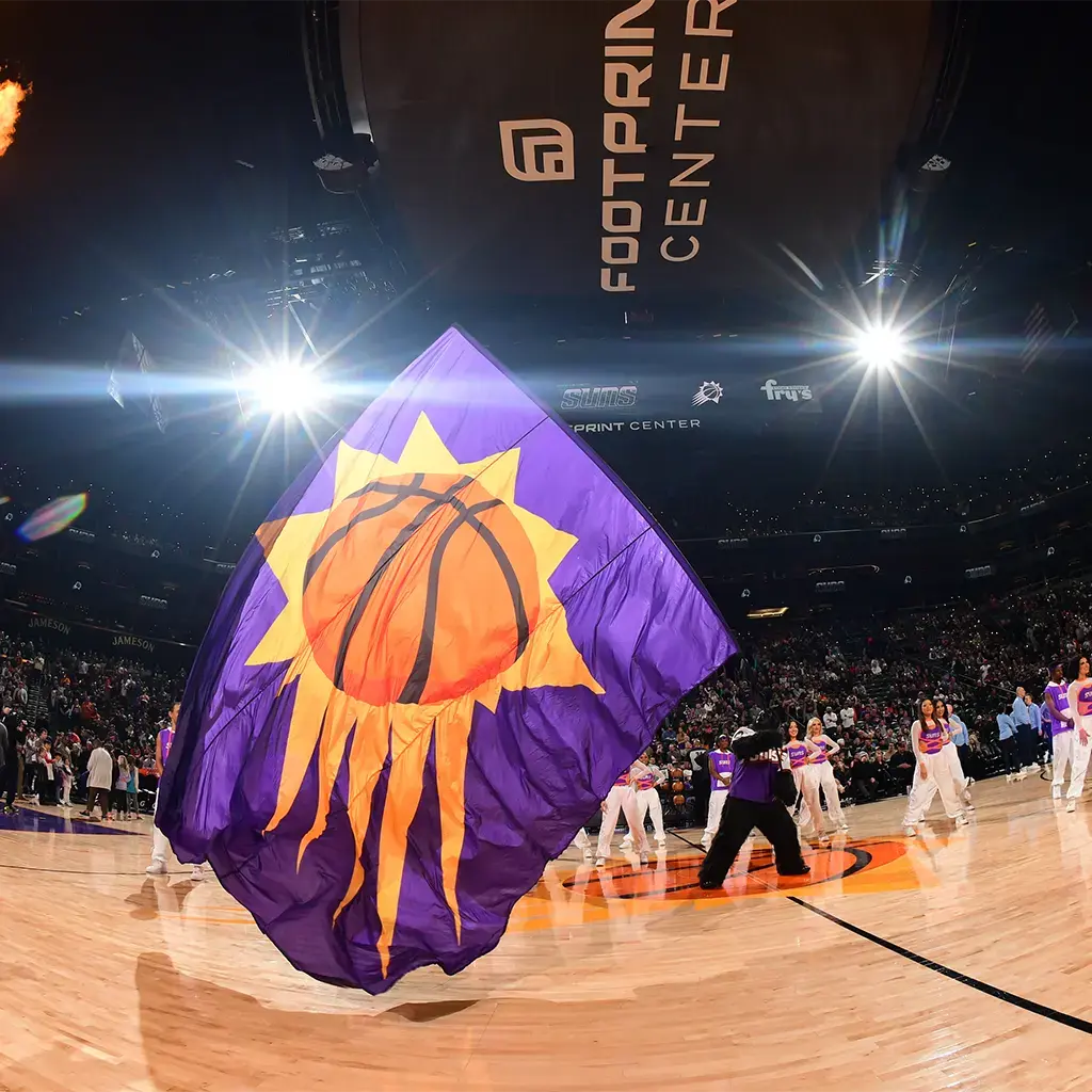 A person waving the Phoenix Suns basketball club flag in the middle of the basketball court