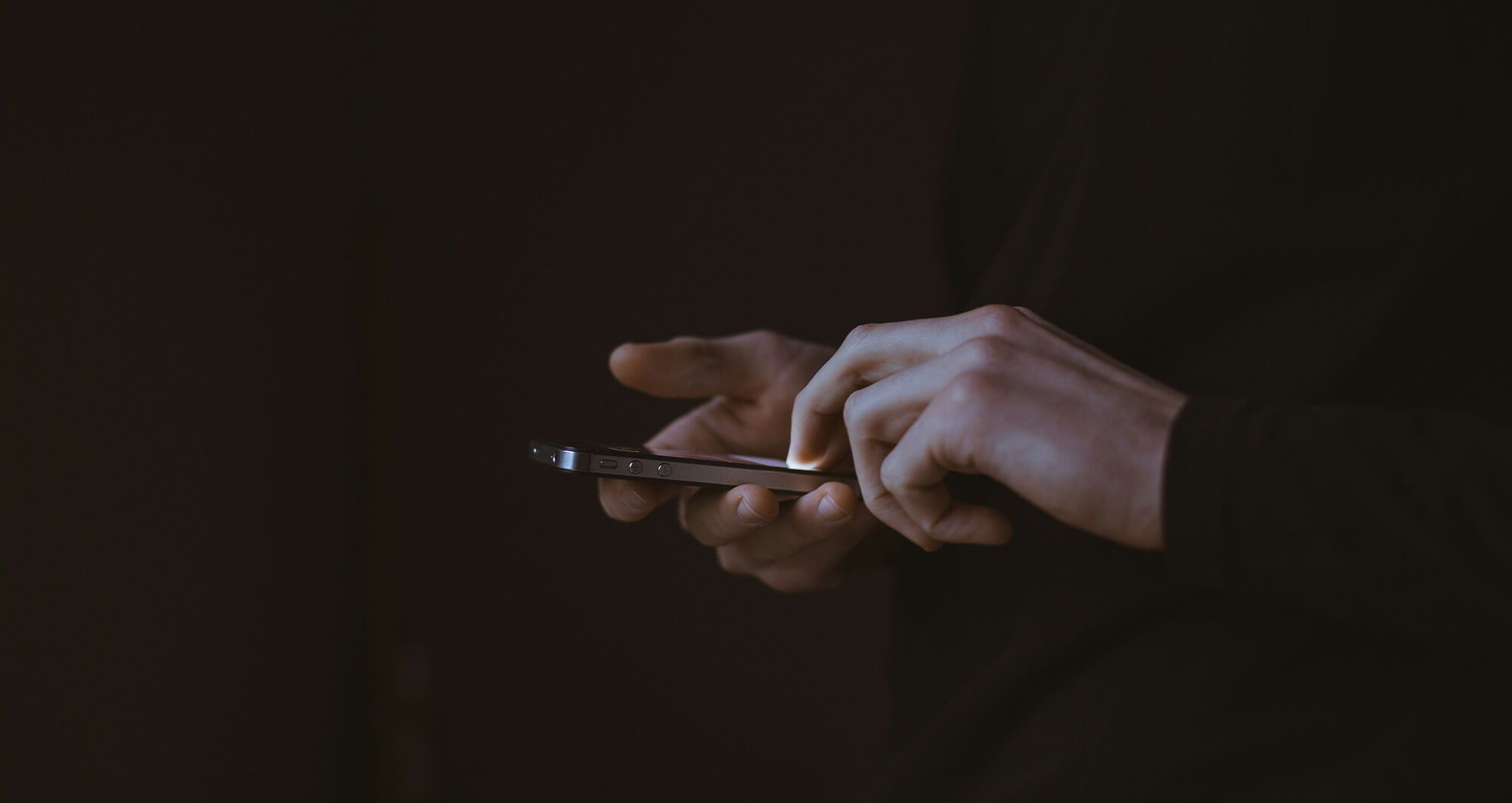 Hands using a smartphone in low light, highlighting secure mobile digital interaction