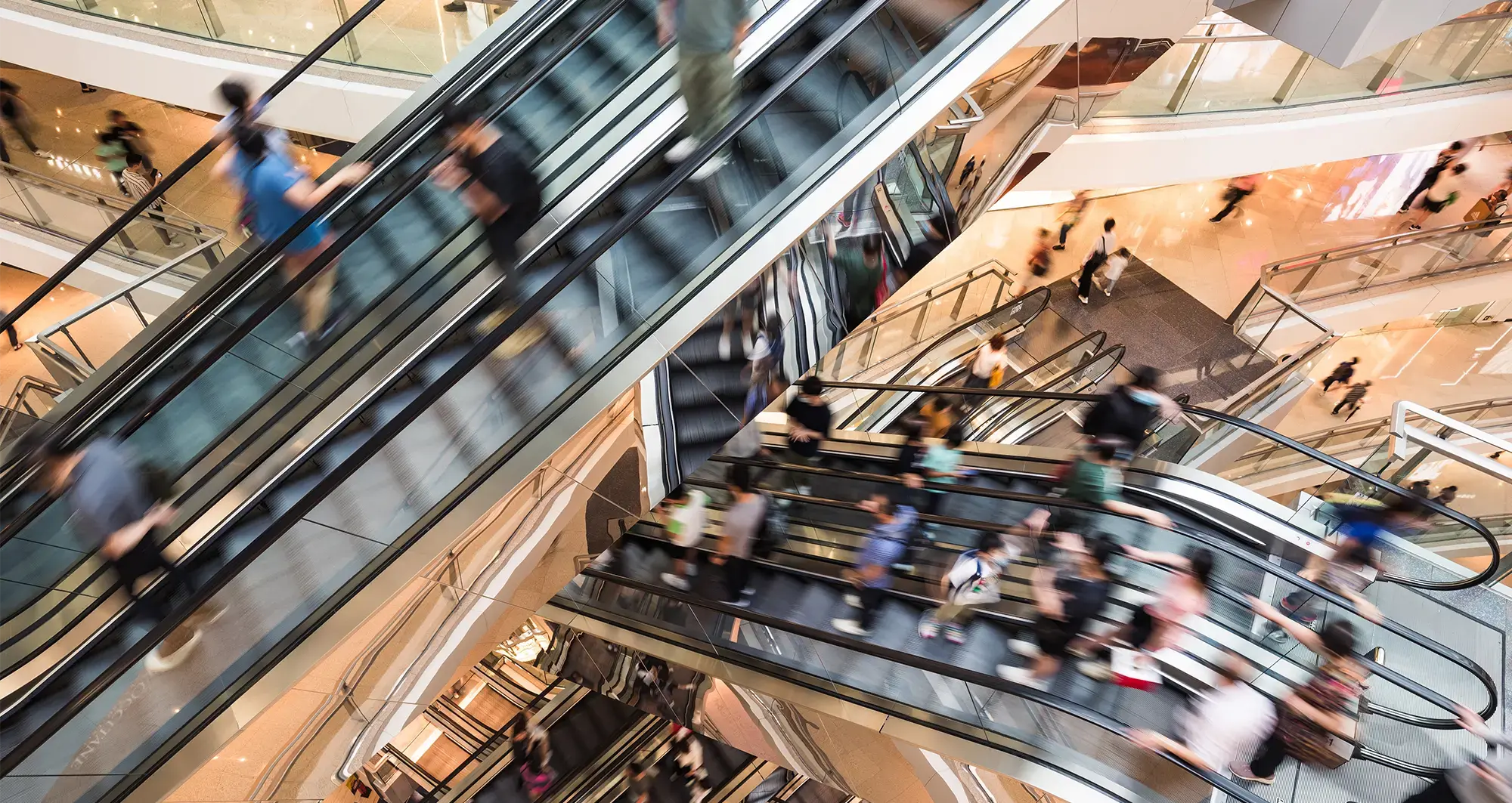 Retail customers riding the escalors in shopping mall