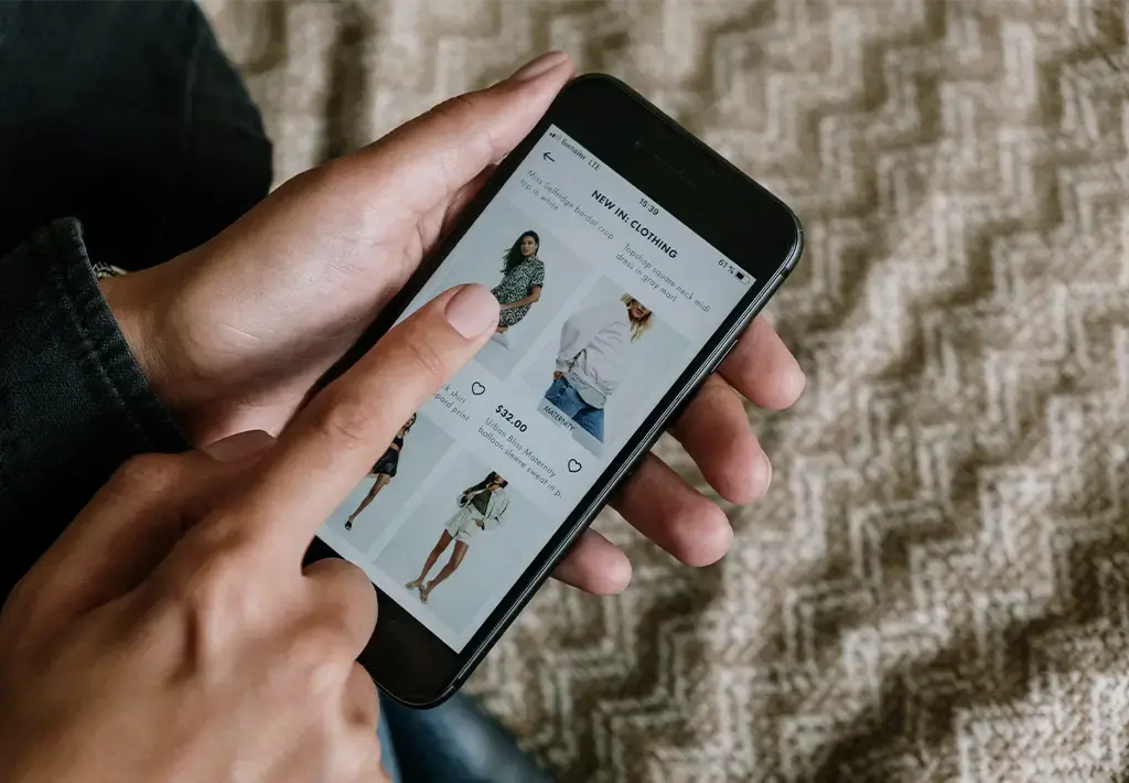 Person browsing a mobile shopping app with clothing options displayed on the screen.