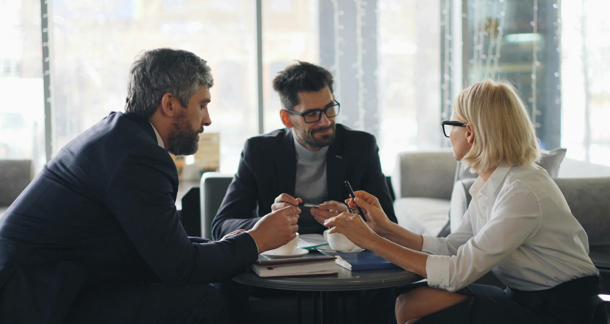 Business consultants discussing digital strategy around a table, reviewing notes and aligning on client solutions