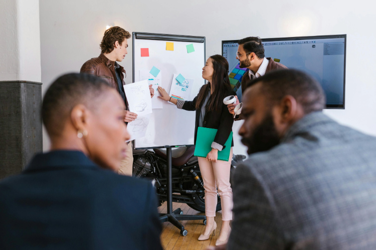 coworkers standing at whiteboard covered in sticky notes