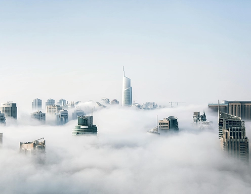 A foggy city skyline with tall buildings disappearing into the mist.