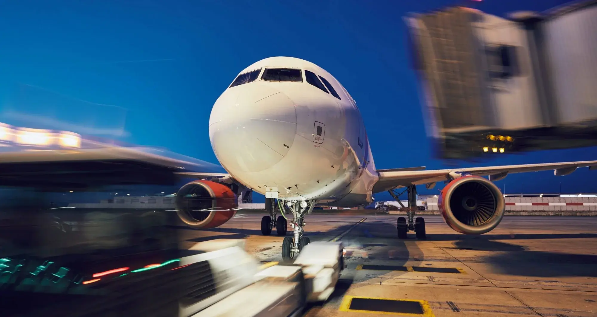 Commercial aircraft at airport gate with ground vehicles, highlighting digital aviation and logistics operations