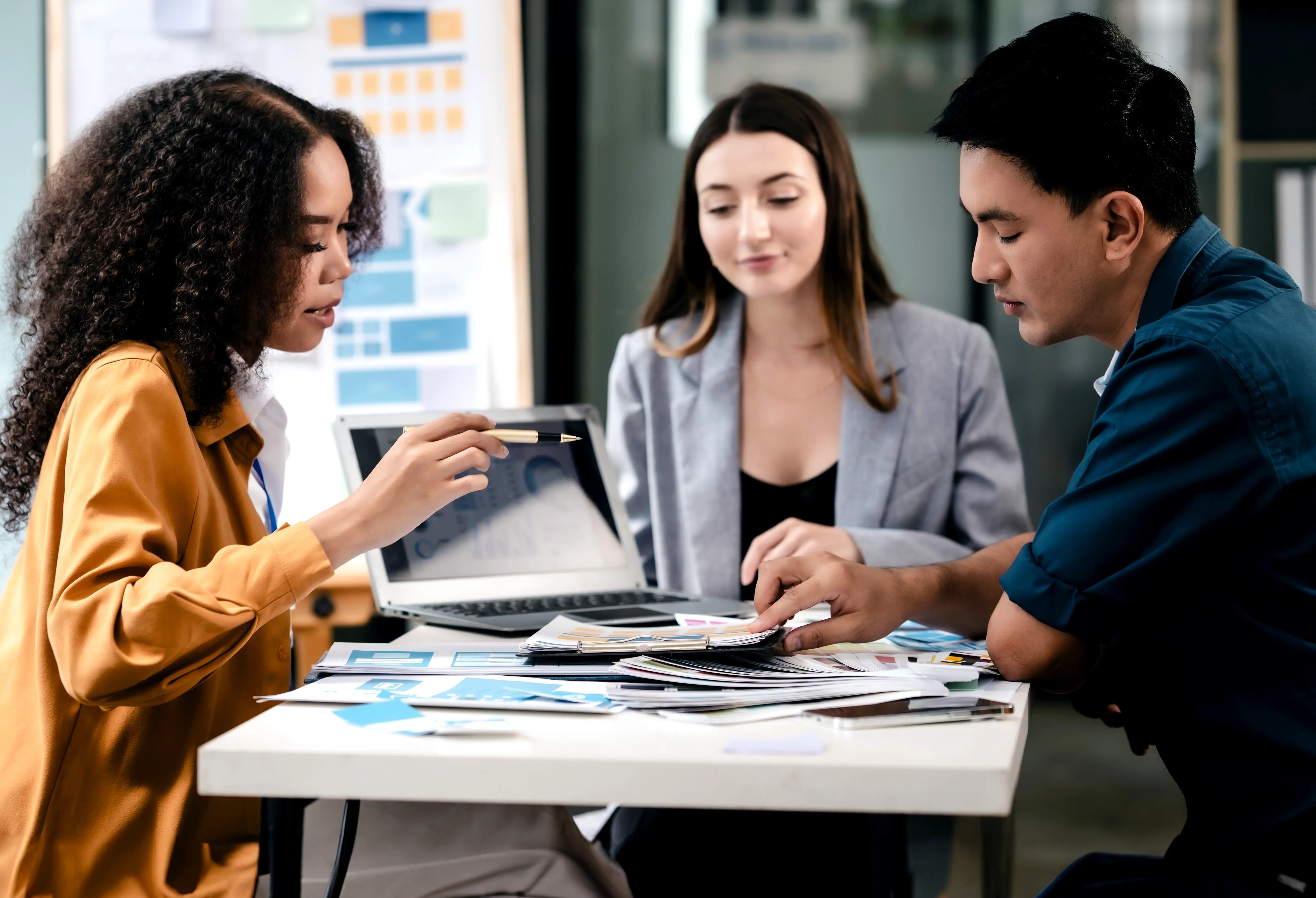 Three people sitting at a table with a laptop, discussing the top 8 e-commerce mistakes brands make and how to fix them.