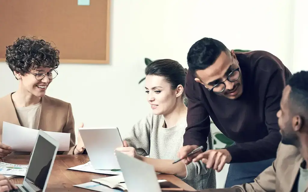 coworkers meeting at table with laptops and paperwork
