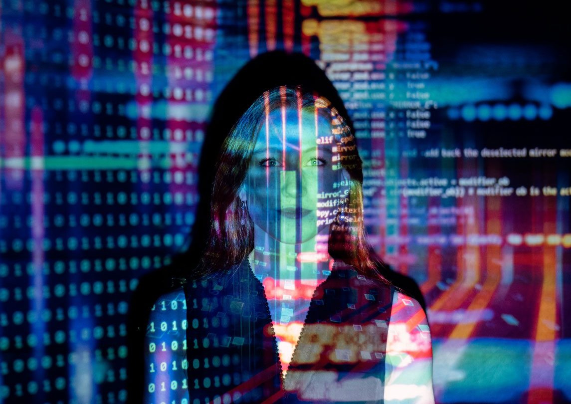 woman standing with data projected onto her and the wall in multicolors
