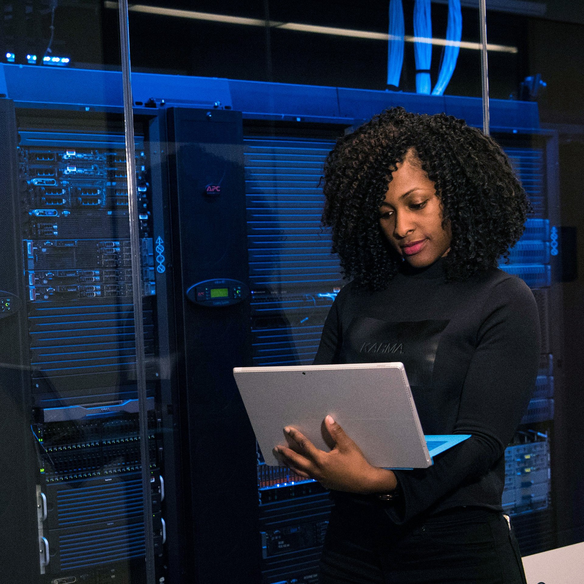 A woman is standing and holding a laptop.