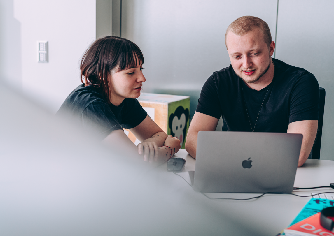 two collegues sitting in front of a laptop discussing challenges of the digital marketplace