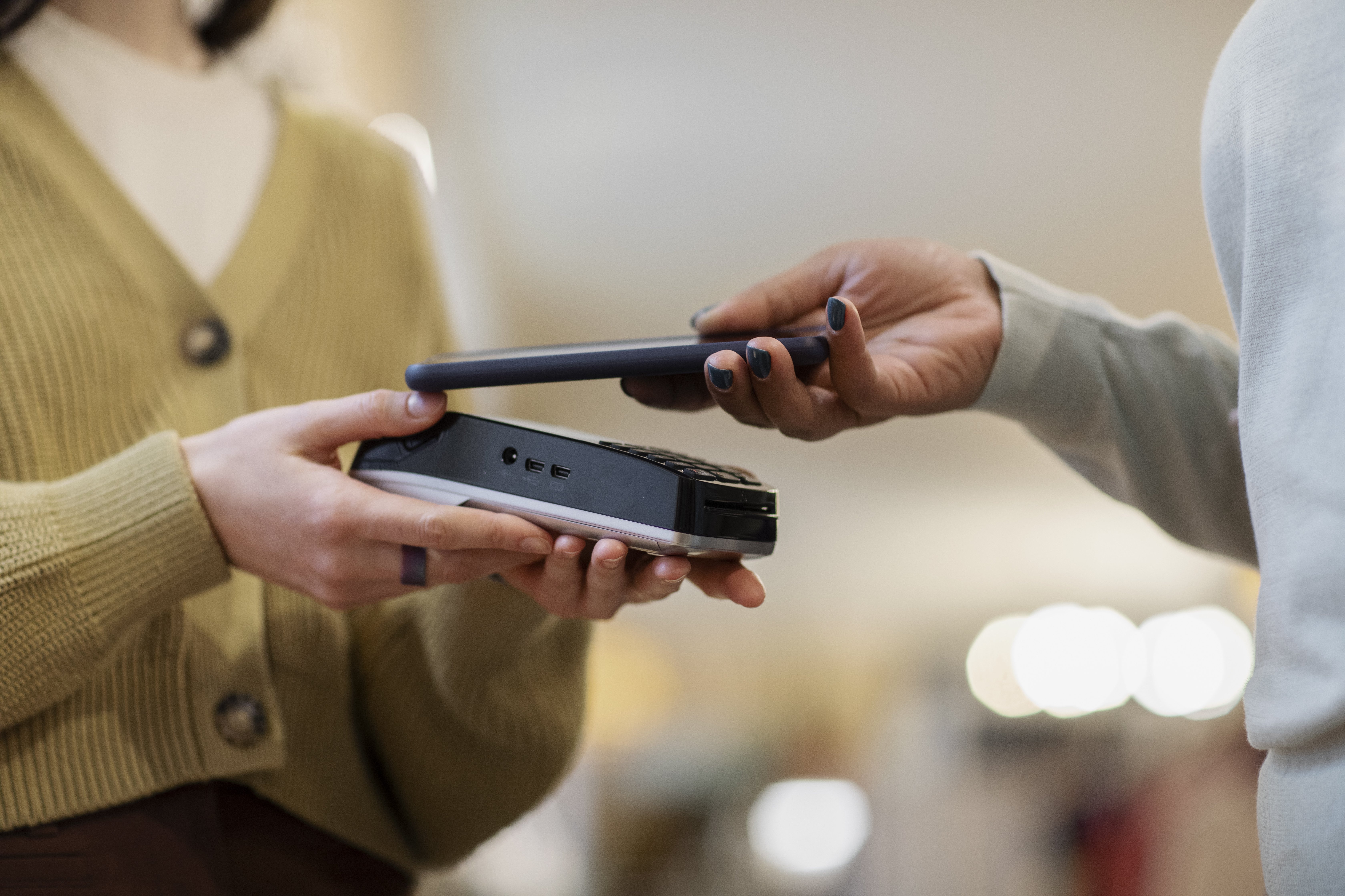 Customer using mobile phone to make a payment to a business woman